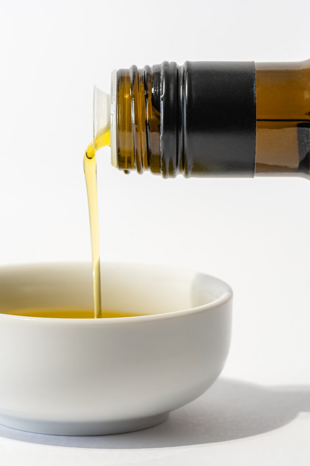 olive oil being poured into a small white dish