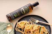 Stavros Kalamata Reserve bottle laid flat on a table with pasta dish on the side