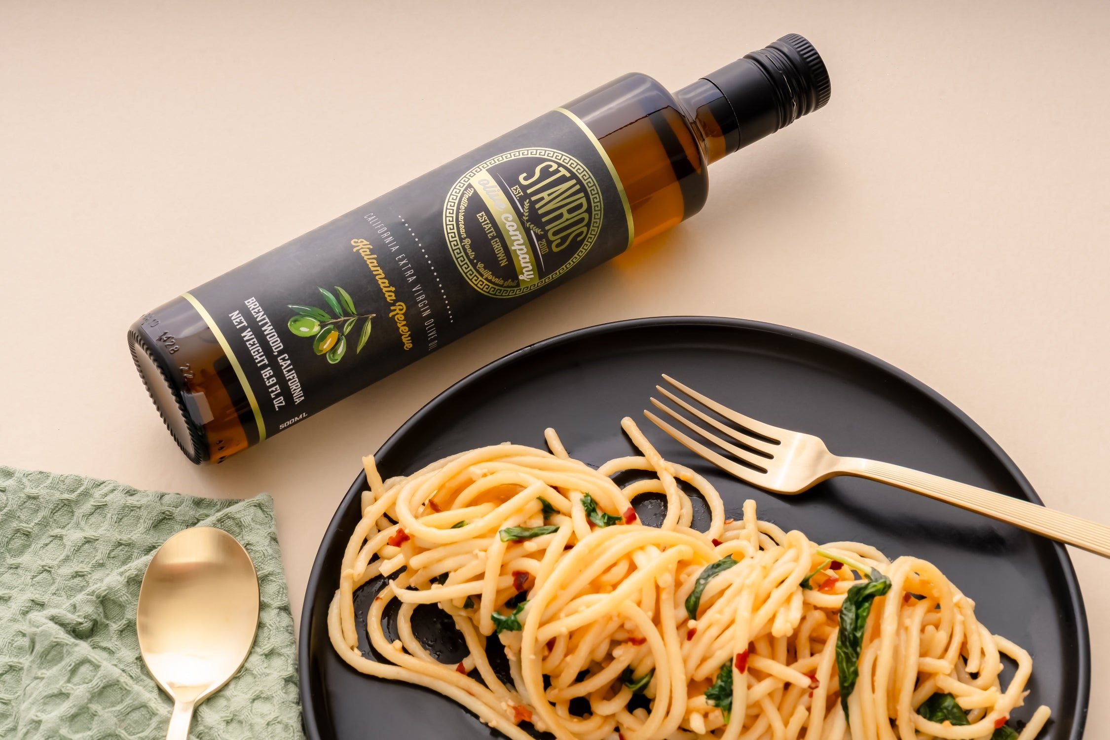 Stavros Kalamata Reserve bottle laid flat on a table with pasta dish on the side