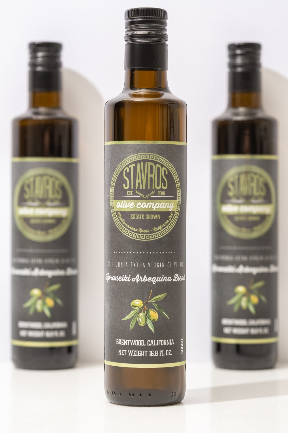 Set of 3 Stavros Koroneiki Arbequina Blend Extra Virgin Olive Oil bottle photographed, with one in focus, and the other two out of focus