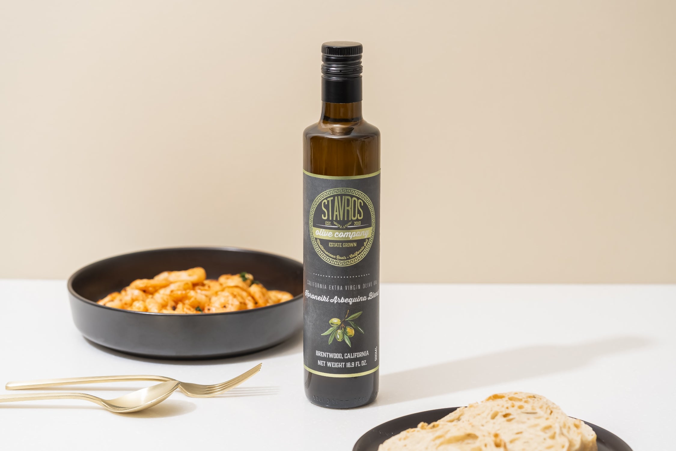 Bottle of Stavros Olive Oil with pasta on a white surface