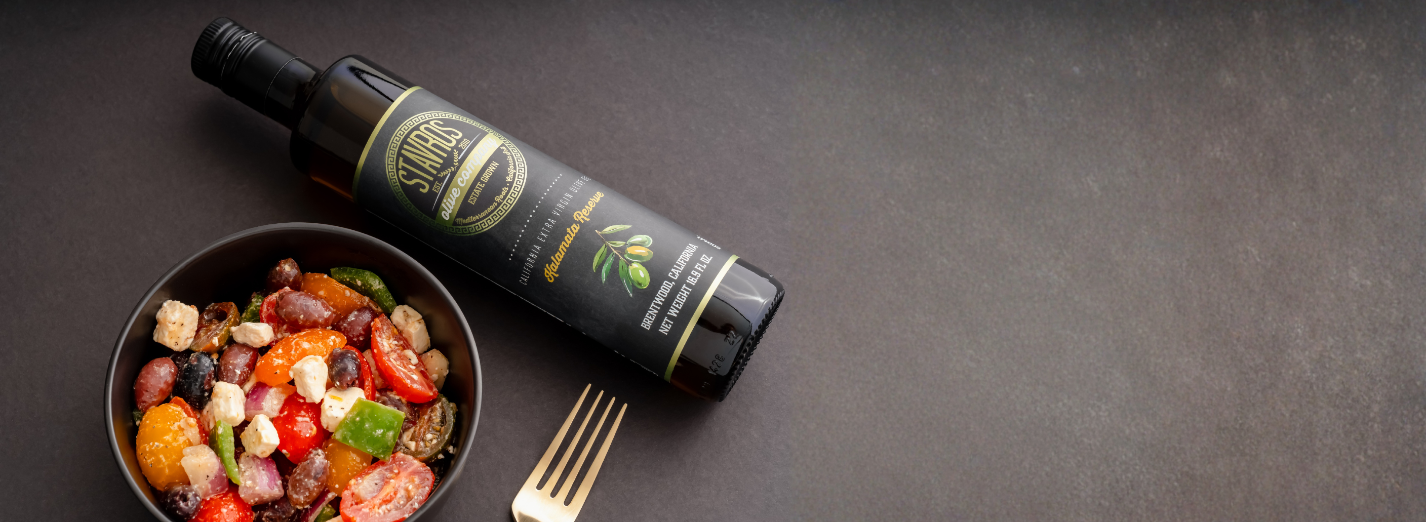 Home Page banner with an aerials view of Stavros Kalamata Reserve Extra Virgin Olive Oil bottle and a greek salad dish on the left 